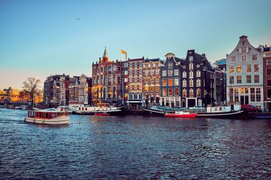 Sonbaharda kentin turistik kesimindeki bir kanalda turistlerle dolu bir tekne. Amsterdam, Hollanda.