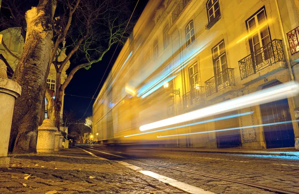 Old tram moves along the street at night in Lisbon, Portugal