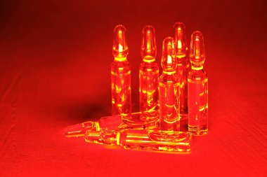 Kırmızı zemin üzerinde cam ampuller halinde antiviral aşı.