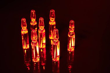 Siyah arka planda ampullerdeki bir virüse karşı turuncu aşı.