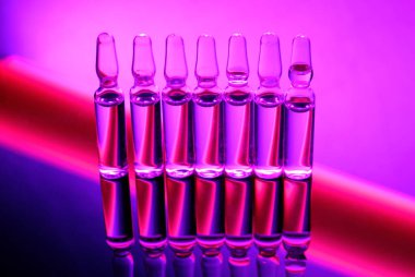 Virüse karşı mor neon arka planda cam ampullerle aşı.