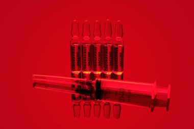 Kavram. Coronavirus / COVID-19 ampullerde kırmızı neon arkaplan üzerinde aşılar.