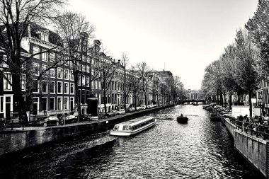 Amsterdam 'daki kanalda turistlerle yaylım ateşi. Siyah-beyaz şehir manzarası.