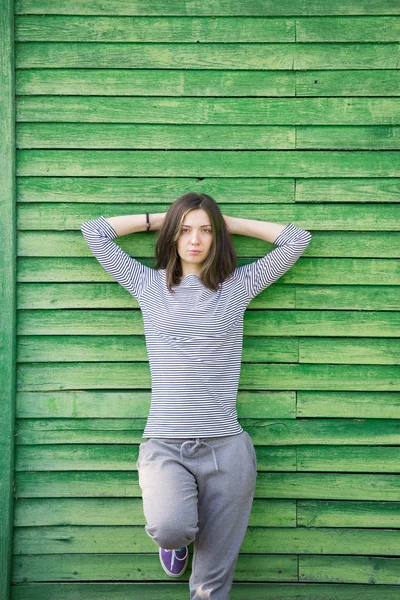 Девушка возле зеленой деревянной стены — стоковое фото
