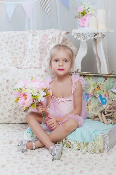 Menina sentada em saco pequeno com flores — Fotografia de Stock