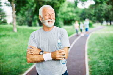 Açık havada egzersiz yaptıktan sonra poz veren mutlu yaşlı bir adamın portresi.