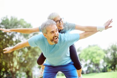 Gülümseyen yaşlı çift parkta birlikte eğleniyor.