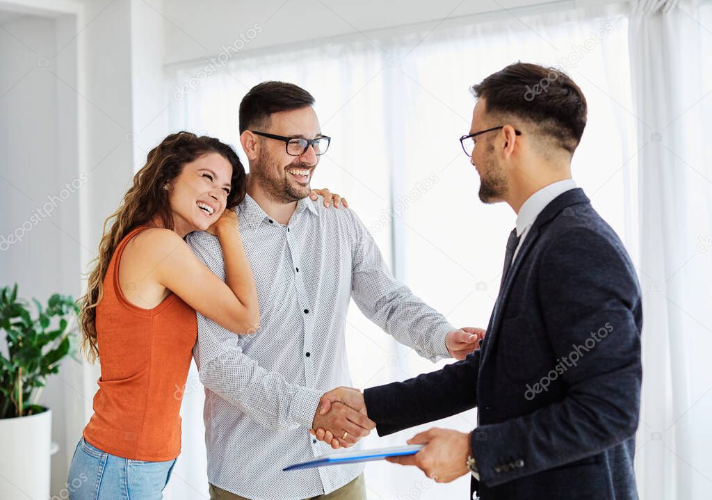 Young happy couple and an agent in a new property