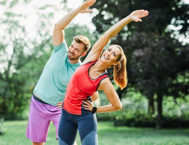 Fitness kadını park egzersiz yaşam tarzı açık hava sporu. Sağlıklı çift, genç formda sporcu esnetiyor.