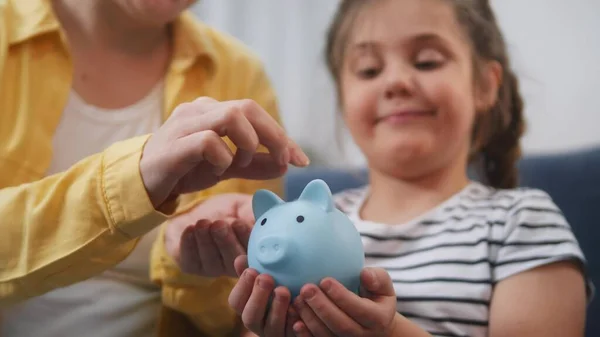 happy family piggy bank. mom and daughter future a put coins in the piggy bank. mortgage loan savings home in crisis coronavirus concept. happy family hoarding money in a piggy bank