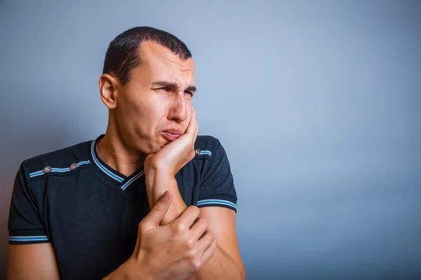 Brunet the man of European appearance with his hand on cheek — Stock Photo, Image