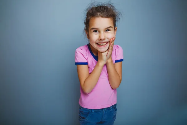 Ragazza bambino a sorpresa mani sul viso su sfondo grigio — Foto Stock