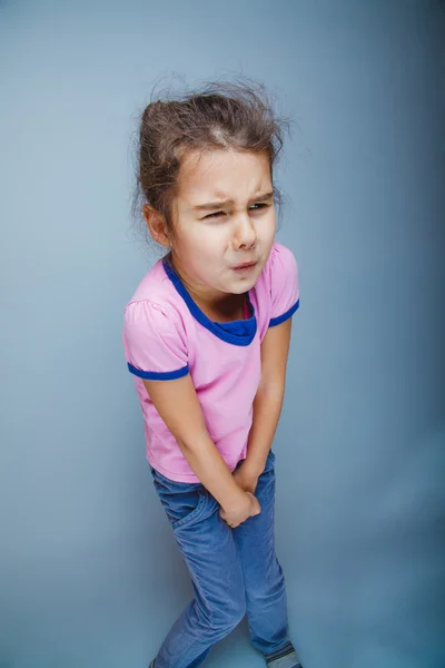 Fille enfant veut vraiment la toilette sur un fond gris — Photo