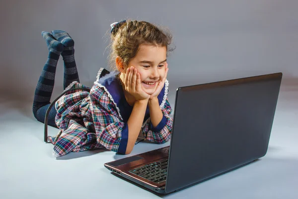 Girl child looking laptop on a gray background — Stock Photo, Image