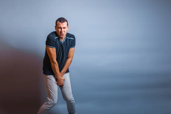 European the man holding his hands over groin in pain on a gray — Stock Image European the man holding his hands over groin in pain on a gray Royalty Free Stock Photos