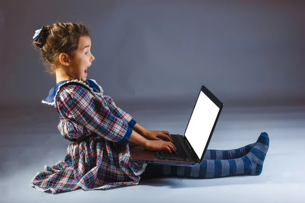 Menina criança olha regozija computador — Fotografia de Stock