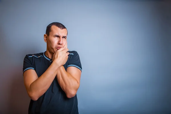 Jaar oude mens van Europees uiterlijk kiespijn op een grijze rug — Stockfoto