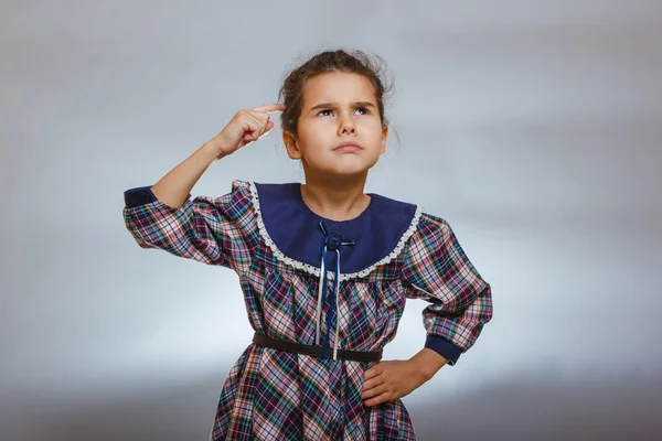 Ragazza bambino pensa dito a testa su uno sfondo grigio — Foto Stock