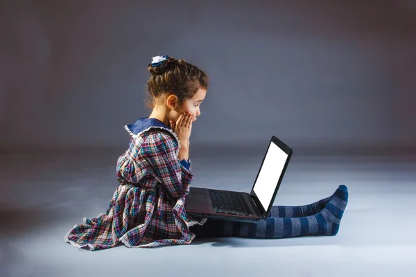 Girl in a colorful dress looking surprised and computer — Stock Photo, Image