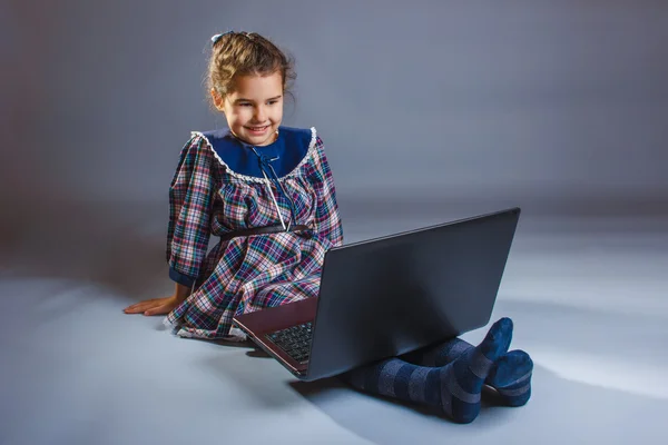 Girl in a dress looks computer — Stock Photo, Image