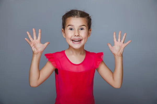 Girl in a red dress held up her hands delight on gray backgrou — Stock Photo, Image