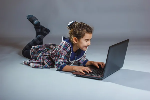 Meisje op zoek netbook en het ervaren van de vreugde op een grijze CHTERGRO — Stockfoto