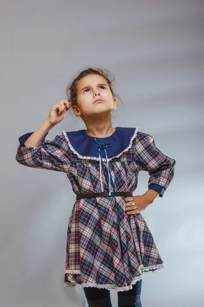 Menina no fundo cinza em um vestido olhando para cima — Fotografia de Stock