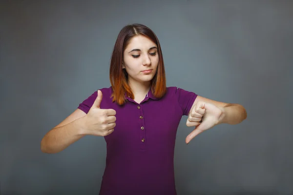 Menina em um fundo cinza mostrando polegares para cima sinal sim e o — Fotografia de Stock