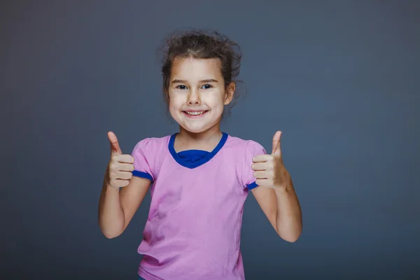 Meisje duimen omhoog teken Ja weergegeven op een grijze achtergrond — Stockfoto