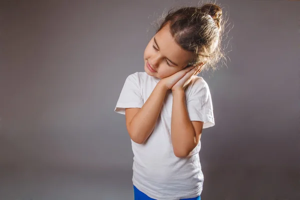 灰色の背景に彼の睡眠で笑っている女の子は彼女の手を置く — ストック写真