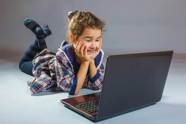 Kleines Mädchen blickt auf Laptop und lächelt Kunst — Stockfoto