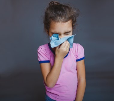 genç kız hasta hapşırma mendil gri arka plan üzerinde olduğunu