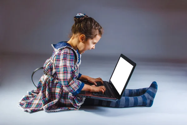 Meisje van de baby boos shouts spelen laptop zit op grijze achtergrond — Stockfoto