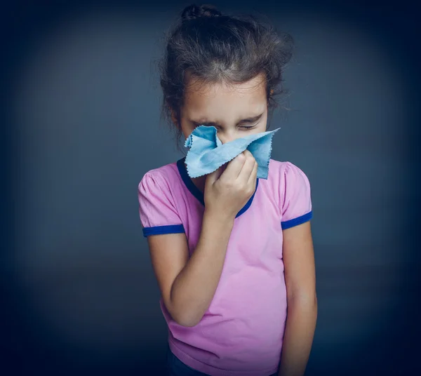 Adolescente chica es enfermo estornudos pañuelo en un gris fondo cros — Foto de Stock