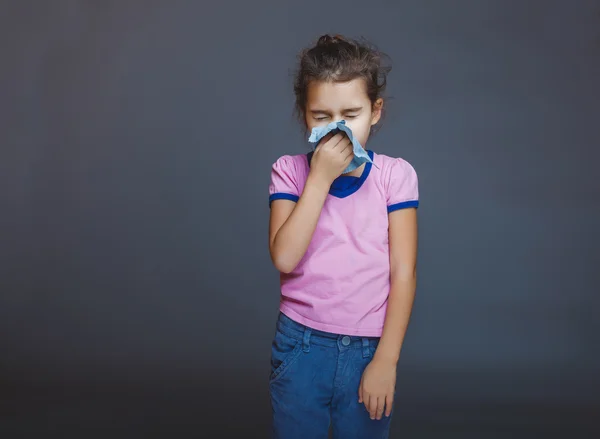 Девочка-подросток страдает носовым платком на сером фоне — стоковое фото