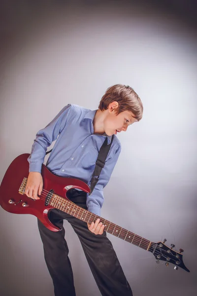 teenager boy of 10 years European appearance playing guitar o