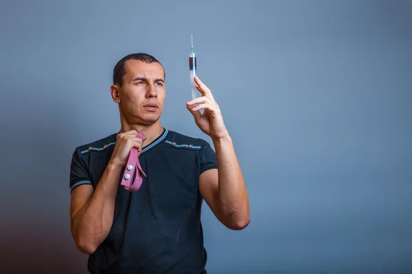 Male of European appearance brunette looking at a syringe with d — Stock Photo, Image