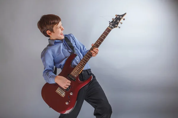 Adolescente chico jugando guitarra en gris fondo — Foto de Stock