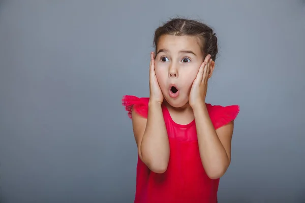 Kırmızı elbiseli kız bebek elleri sürpriz yüzünde koymak. — Stok fotoğraf