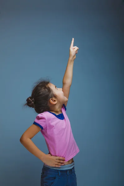 Adolescente niña apuntando al cielo sobre fondo gris — Foto de Stock