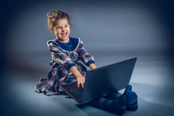 Teen girl  the floor playing laptop surprised on gray — Stock Photo, Image