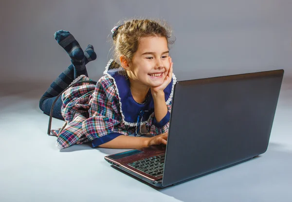 Teenager-Mädchen spielt Laptop auf grauem Hintergrund — Stockfoto