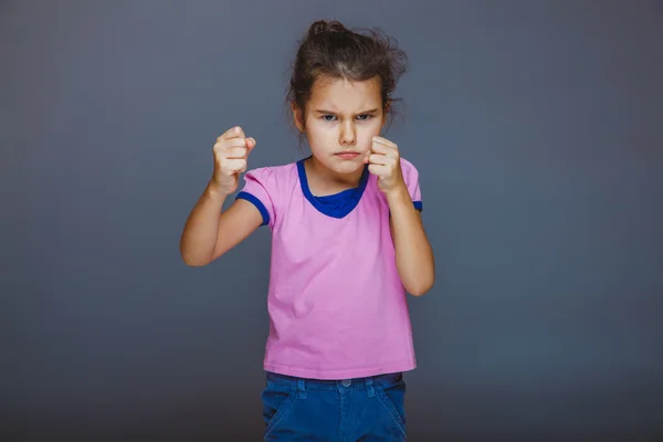 Teen girl shows angry fists on gray background — Stock Photo, Image