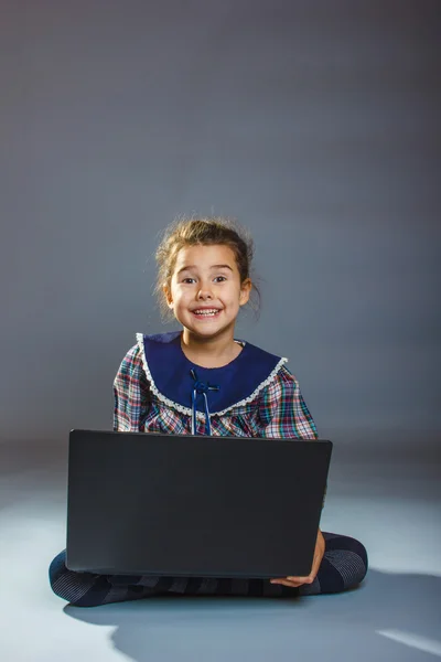 Dziewczyna siedzi na podłodze gra laptopa szara — Zdjęcie stockowe