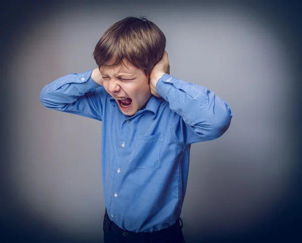 Teenager boy closed  ears with his hands on gray background — Stock Photo, Image