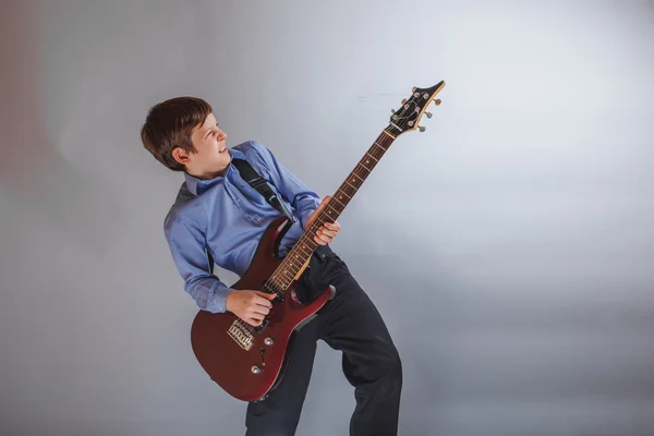 Teenager boy Dark Brown European appearance playing guitar joy o — Stock Photo, Image