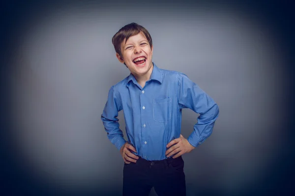 Adolescente chico disfruta riendo en gris fondo cruz proceso — Foto de Stock