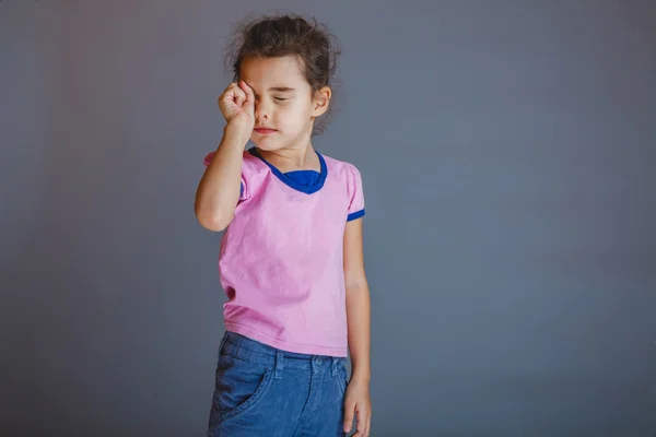 Anak gadis itu lelah menggosok matanya pada latar belakang abu-abu — Stok Foto