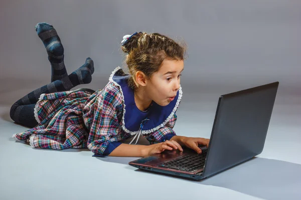 The girl child is playing in a notebook on gray background — Stock Photo, Image