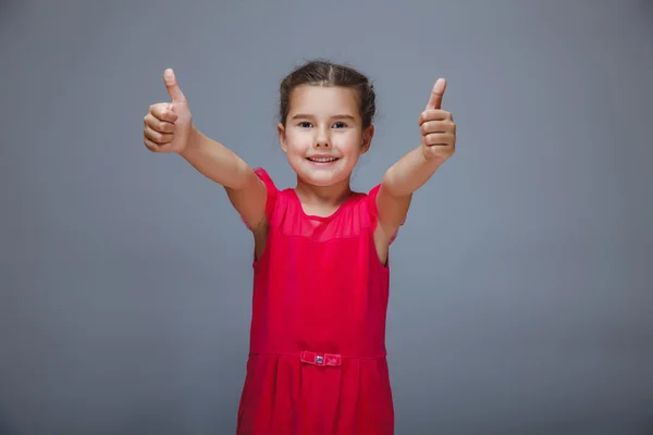 La niña está mostrando los pulgares hacia arriba gesto sí en un backgr gris — Foto de Stock